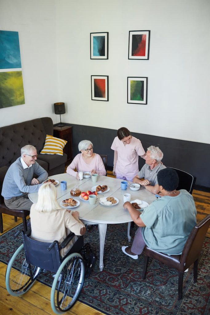 Diverse group of seniors enjoying breakfast with caregivers in a supportive community setting